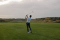 Golfer completing a full swing follow-through, demonstrating body connection